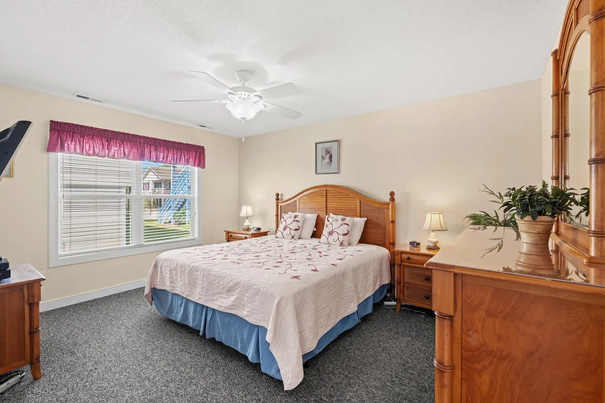 This image features a spacious bedroom with a well-made bed, a window allowing natural light to filter in, dressers, and bedside lamps. The atmosphere is inviting and peaceful, perfect for winding down or waking up refreshed.