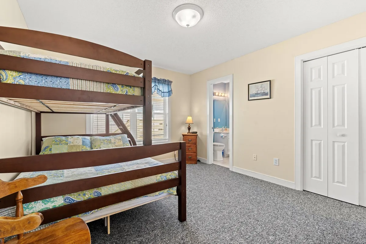 A pyramid bunk bedroom is depicted here, with a sturdy bunk bed, a nightstand and lamp, and an access door to the bathroom. The mood is relaxed and playful, hinting at family bonding and bedtime stories.